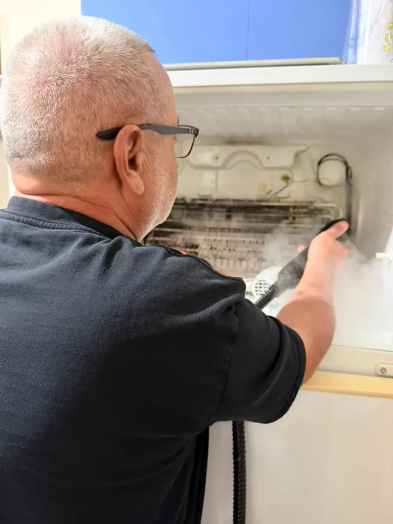 Quality Appliance Repairs technician steam cleaning a mouldy fridge evaporator coil in a Sydney home