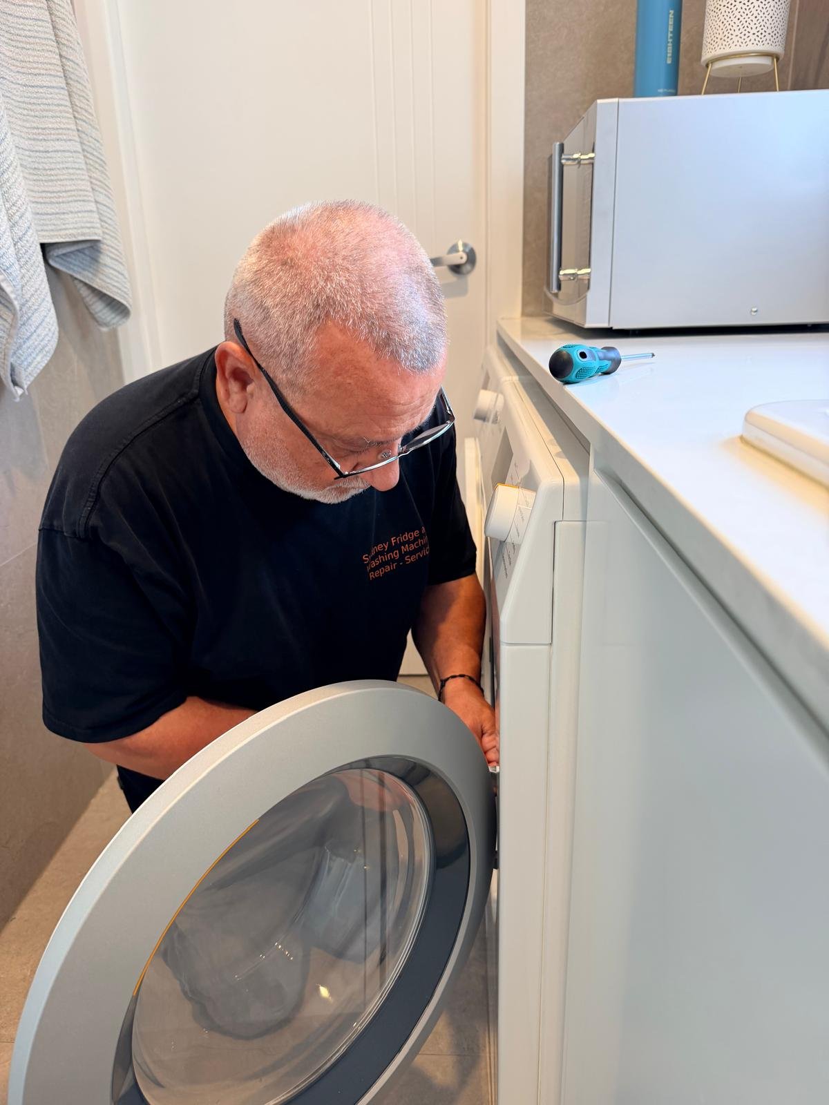 Quality Appliance Repairs technician replacing a drain pump on a front loader washing machine in Sydney