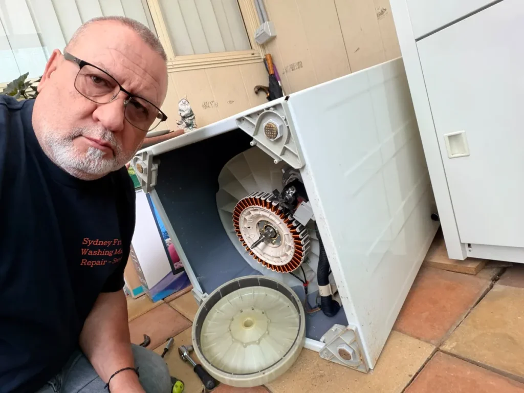 Technician beside a washing machine opened up to replace the direct-drive motor stator in Sydney