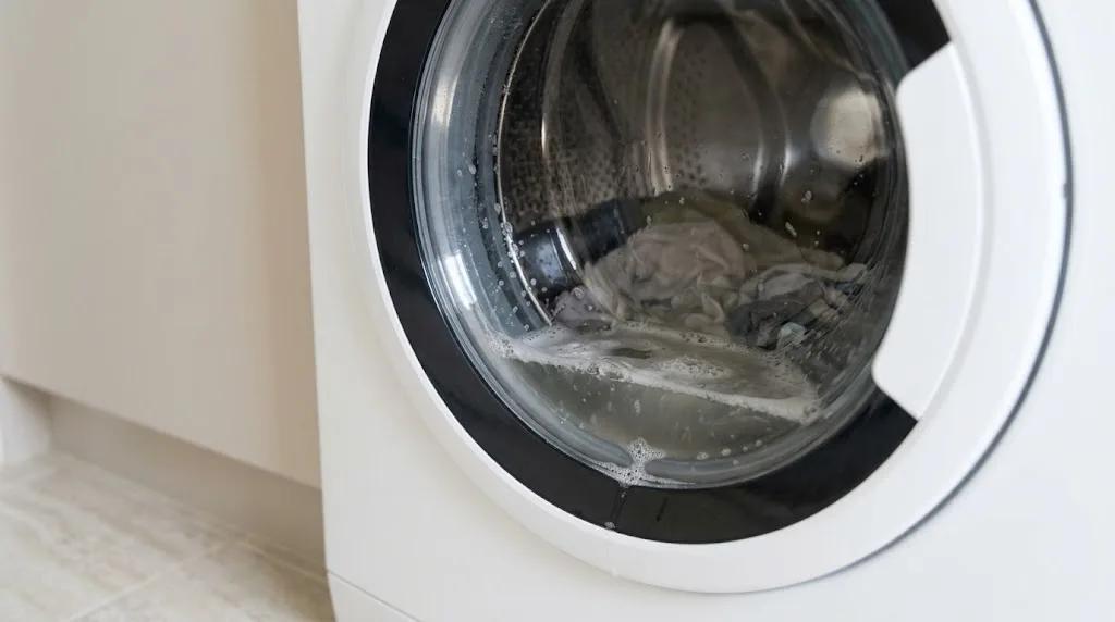 Front-loader washing machine door with soapy water left in the drum after the cycle